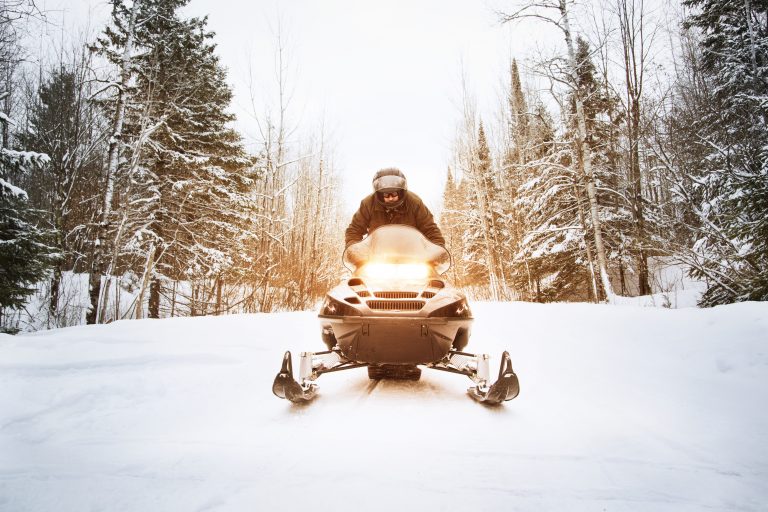 Man Riding Snowmobile On Footpath Amidst Forest